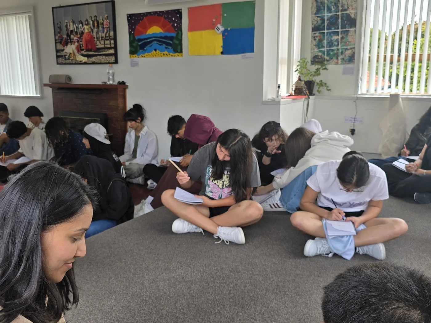 Rangatahi writing on the floor of a workshop room.